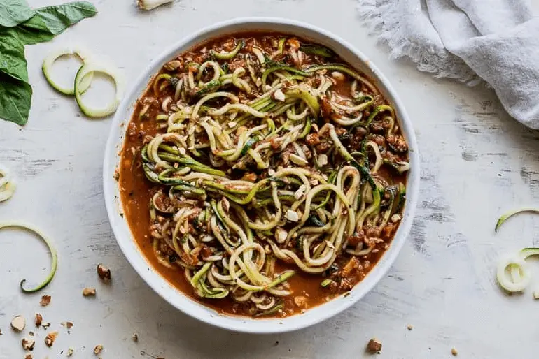 Overhead view of a bowl of pesto zucchini zoodles made with Muir Glen Organic Fire Roasted Tomatoes.