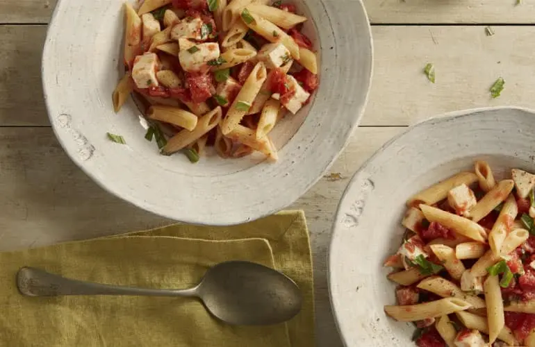 Two bowls of pasta topped with Muir Glen Organic Portabella Mushroom Pasta Sauce, cheese and herbs.