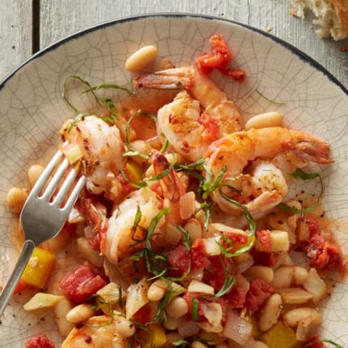 Plate of shrimp and white bean provencal garnished with fresh herbs
