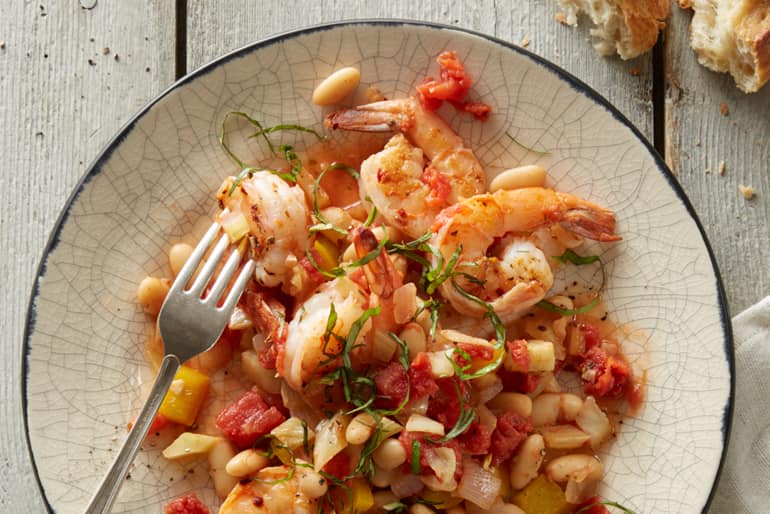 Plate of shrimp and white bean provencal garnished with fresh herbs