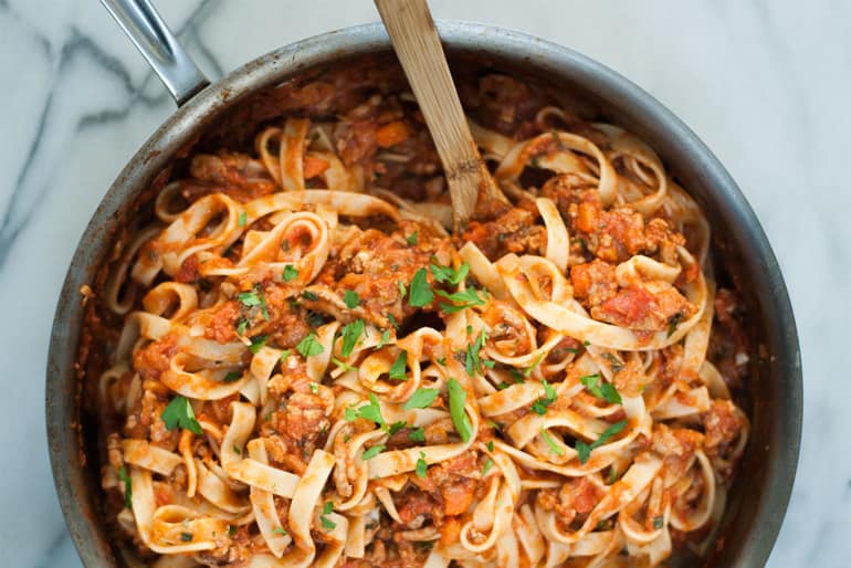 A pot with fettuccine turkey bolognese and a wooden spoon