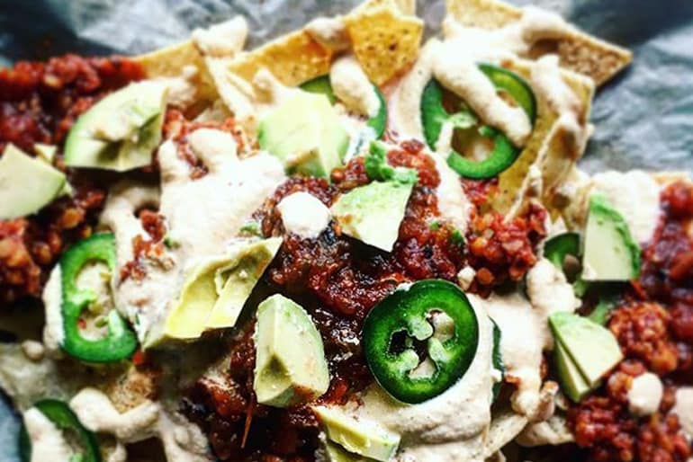 Nachos made with Muir Glen Fire Roasted Diced Tomatoes topped with smoky red lentils, avocado, jalapenos and cashew cheese sauce.