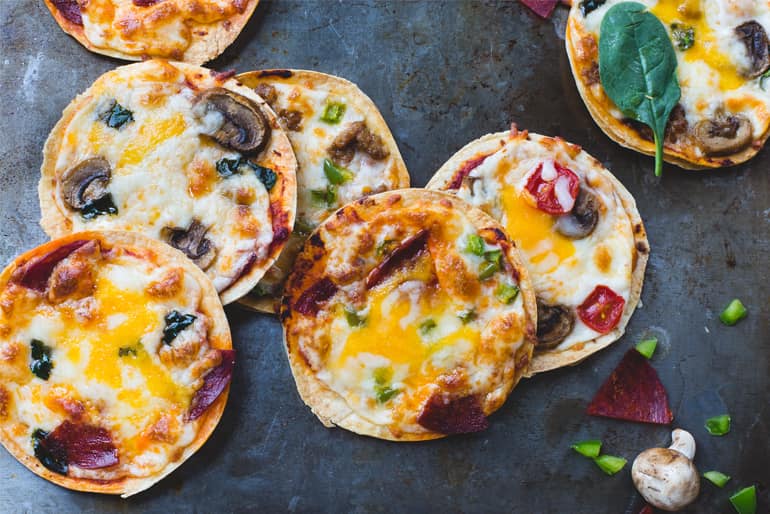 Mini pizzas topped with cheese, mushroom, tomato and salami