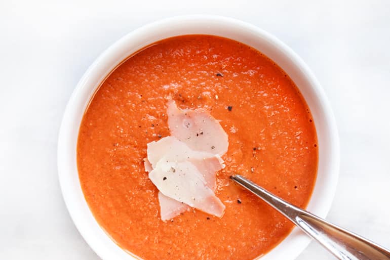 A bowl of tomato soup made with Muir Glen Whole Peeled Tomatoes topped with shaved parmesan.