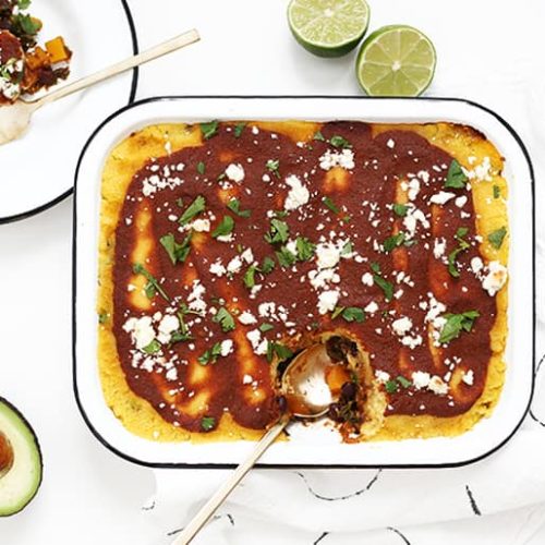 Butternut kale tamale bake next to a plate of food with limes and avocado
