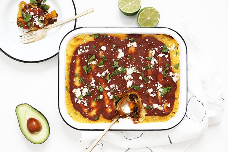 Butternut kale tamale bake next to a plate of food with limes and avocado