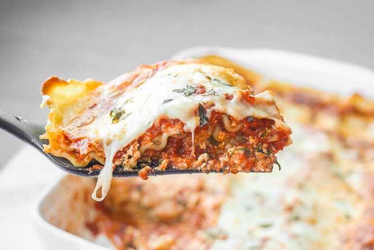 Slice of creamy spinach and tomato vegetarian lasagna