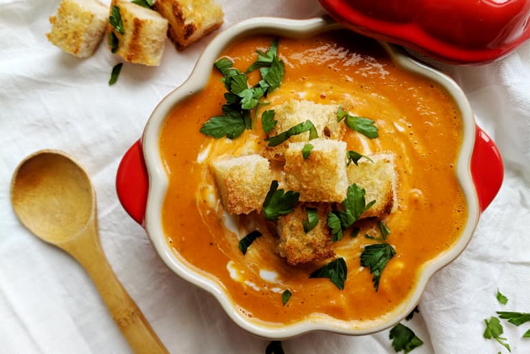 Bowl of tomato and pumpkin bisque topped with croutons and parsley
