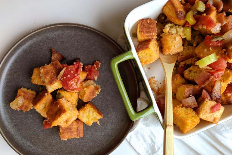 A dish of cornbread stuffing made with Muir Glen Whole Peeled Tomatoes, San Marzano Style and bacon served on a round plate.