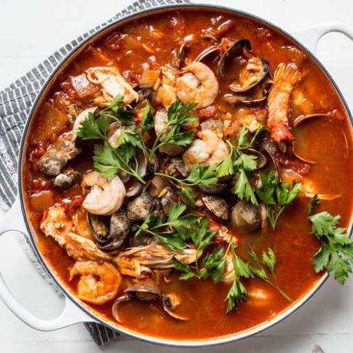 Overhead view of a pot of cioppino made with Muir Glen Tomato products topped with flat leaf parsley.
