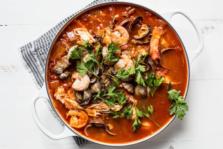 Overhead view of a pot of cioppino made with Muir Glen Tomato products topped with flat leaf parsley.