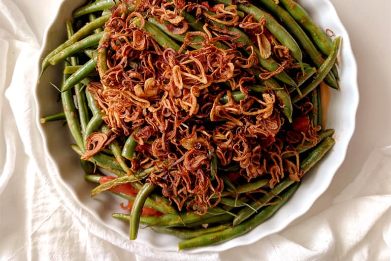 A dish of lebanese green beans topped with crispy shallots